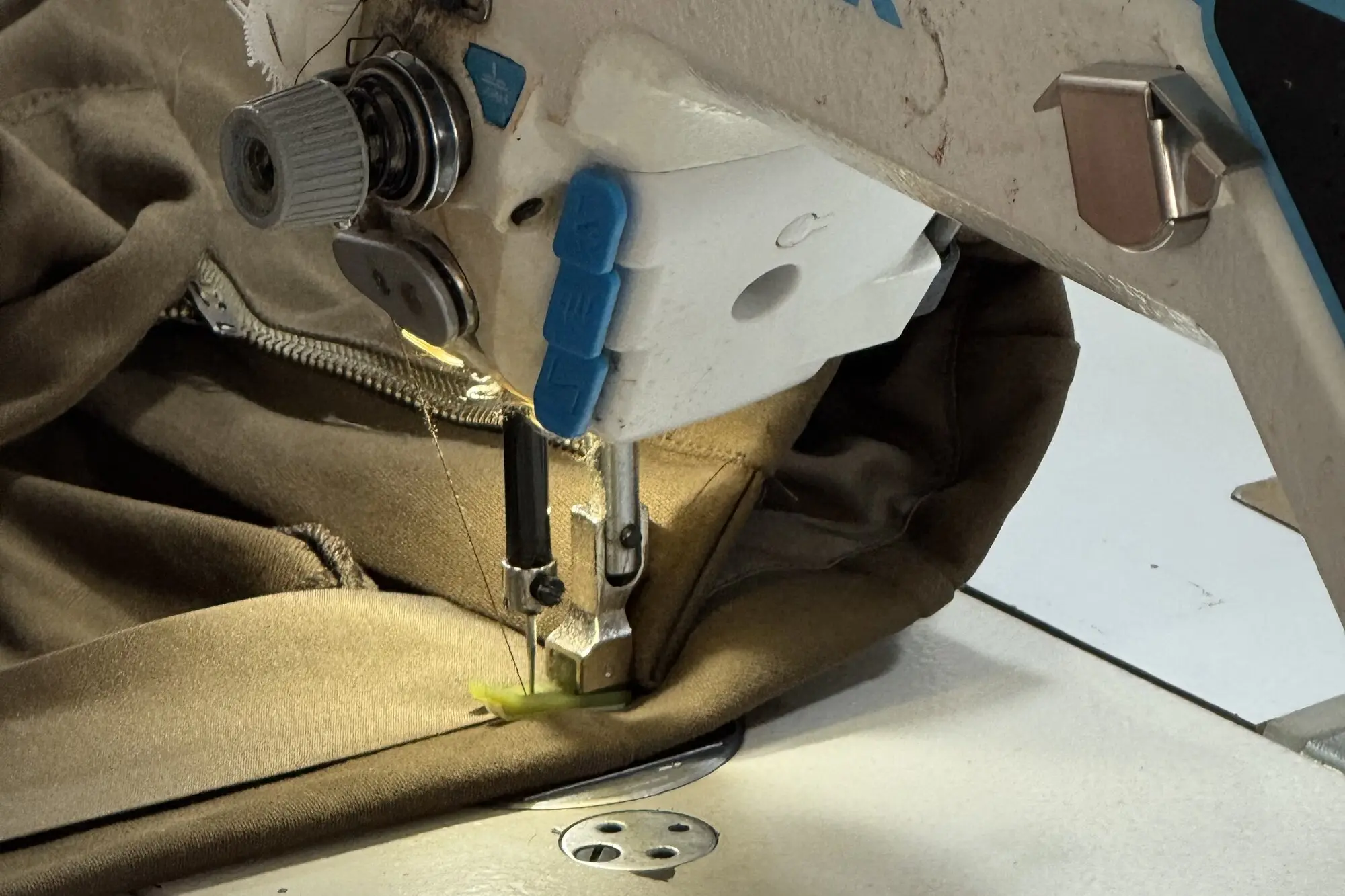 close-up of a Jack industrial lockstitch machine needle and presser foot stitching a khaki panel on the ApronCraft sewing line