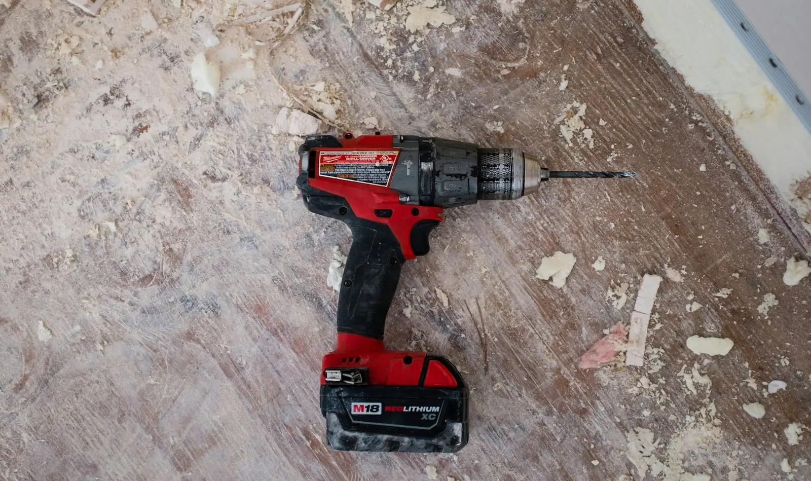 cordless drill resting on a sawdust-covered woodworking bench