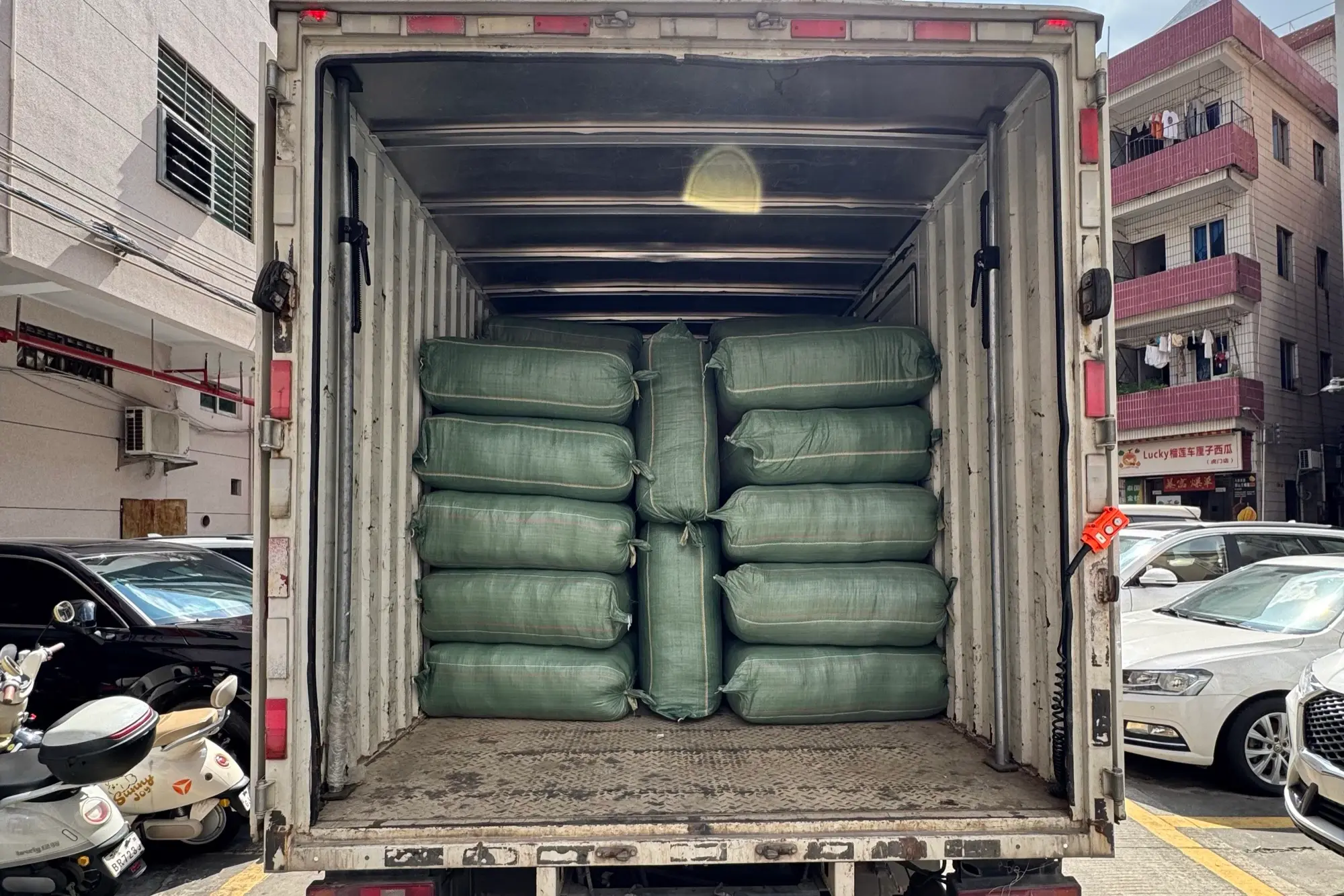 finished order packed in sealed woven poly bales, stacked inside a box truck at the factory loading bay for sea freight